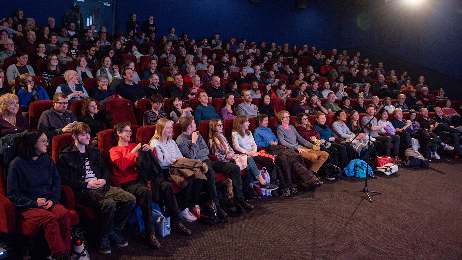 A full festival audience in red cinema seats before a post-screening Q&A